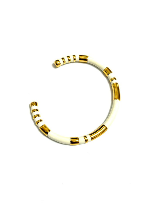 Elodie Cuff in black enamel with gold-tone segments on white background. A bold chic bangle bracelet with a gold-plated finish, featuring black stripes and branded with the name 'BOLD'.