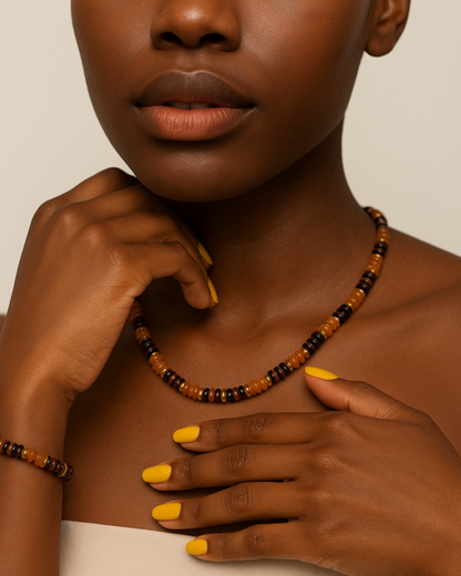 Close-up of a women wearing a beaded necklace with a neutral background. Handmade Una beaded jewelry set with gold-tone accents.
