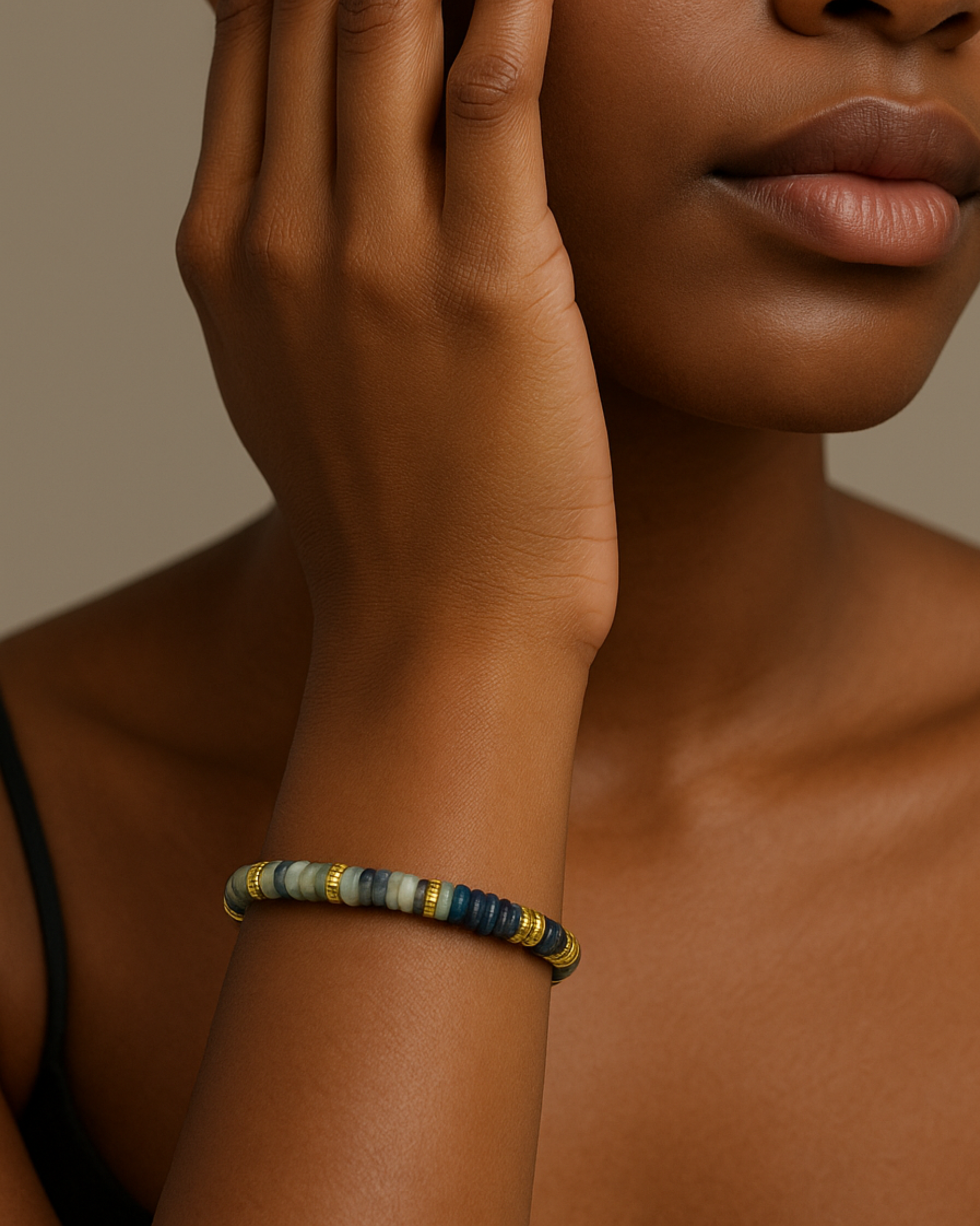 Close-up of a person wearing a beaded bracelet on a neutral background. Indigo Set Bracelet Featuring Indigo Beads and Gold Detailing