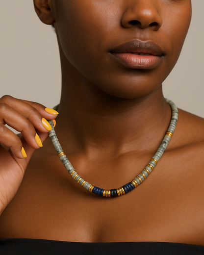 Female wearing a beaded necklace with a neutral background.Indigo Set Necklace  Grey and Indigo Beads with Gold Accents on model