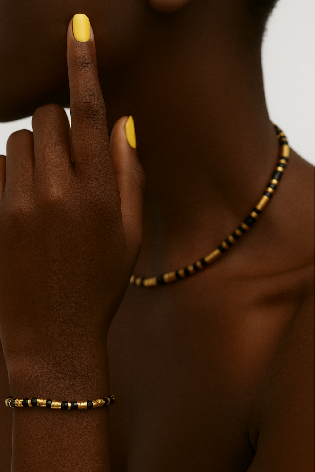 Person women a black and gold beaded necklace and bracelet with yellow nail polish. Close-up of Eona Black Set showing gold and black stainless-steel beads